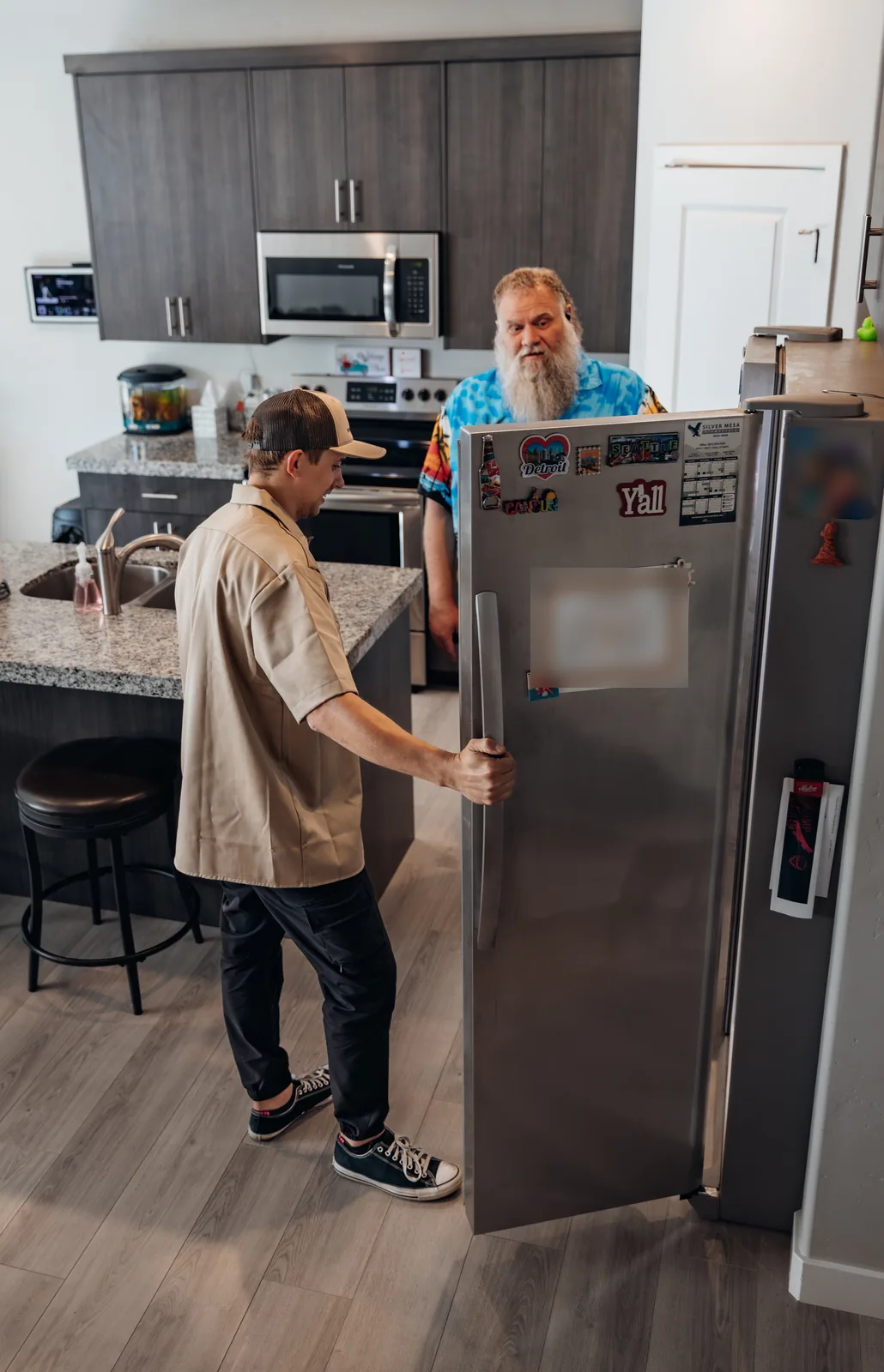 Blake from PowerClean holding the open door of a stainless steel refrigerator as a customer looks at him over the top of it